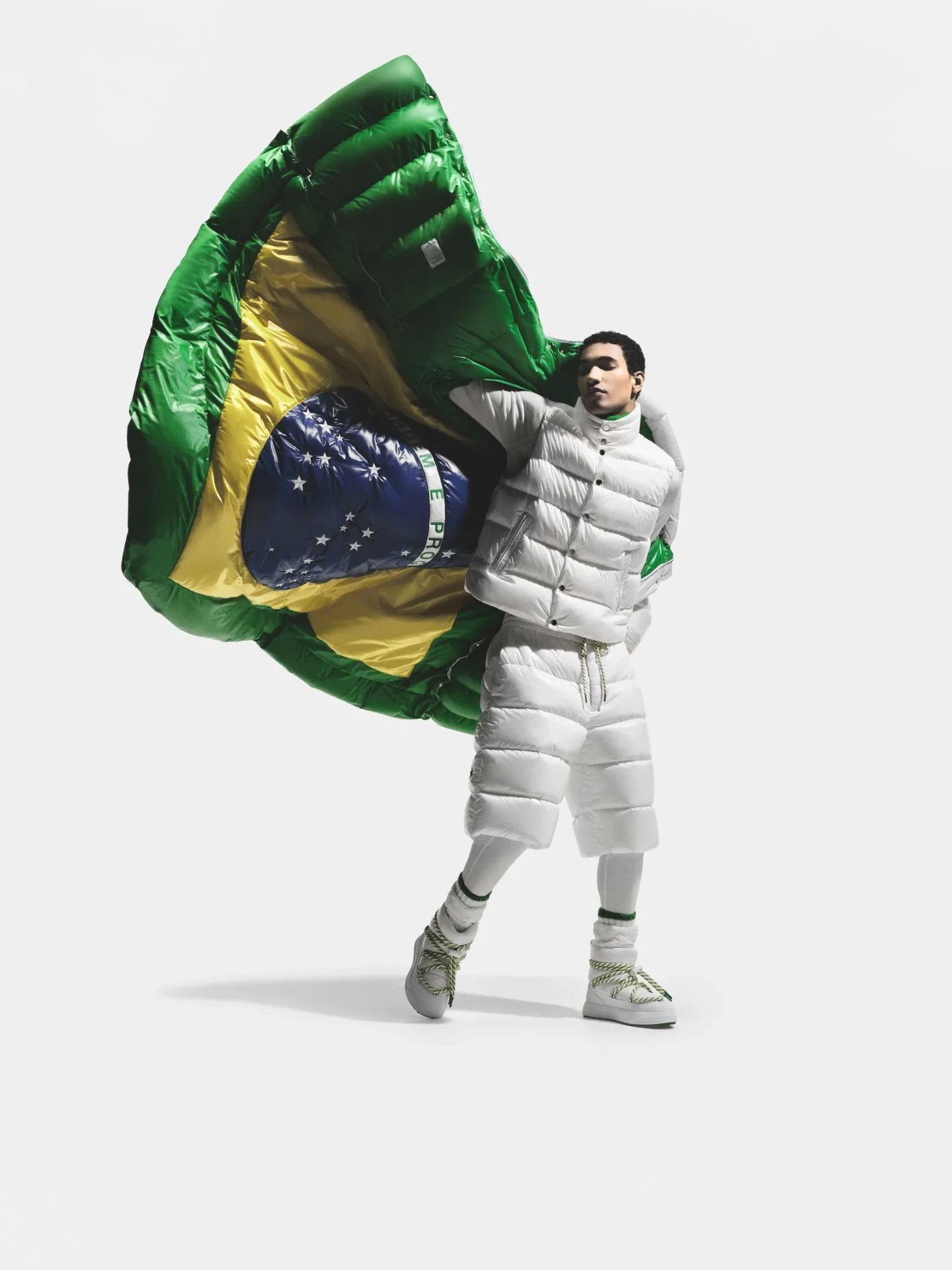 Model in white Moncler puffer set holding an oversized padded Brazilian flag
